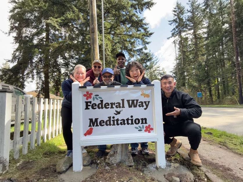 Members of Federal Way Meditation together at the center sign